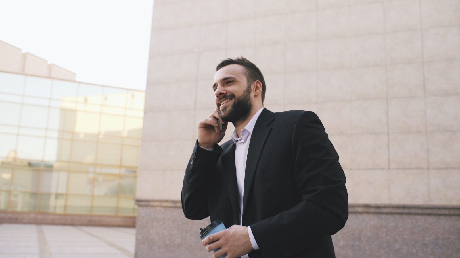 Man in suit talking on phone holding coffee cup